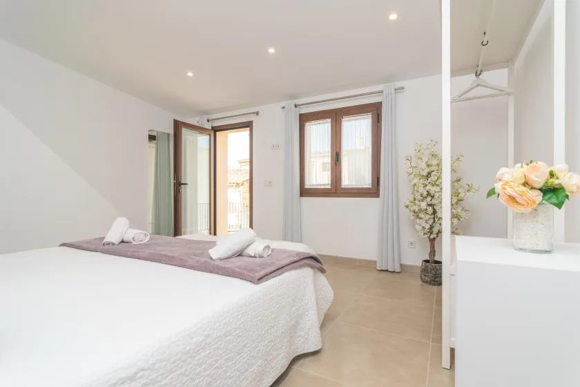 A bright bedroom with a bed, a window, and an open doorway.