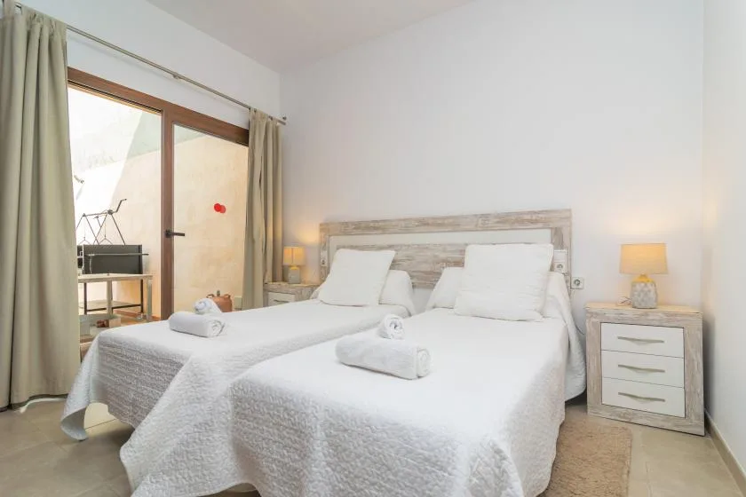 A bright bedroom with two beds, white bedding, and bedside lamps.