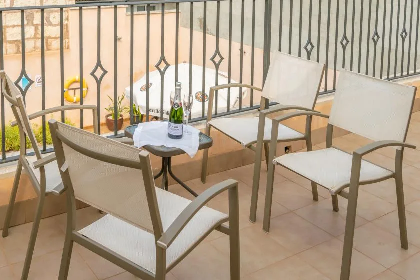 A small balcony seating area with chairs around a table beside a metal railing.