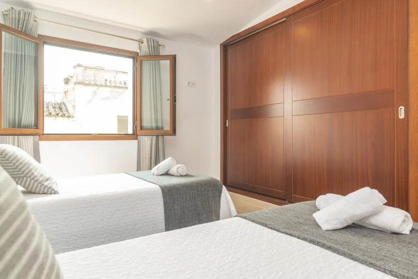 A bedroom with two beds and an open window.