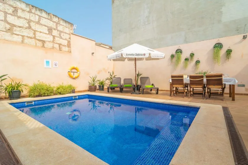 A courtyard pool with lounge seating and a dining table beside it.