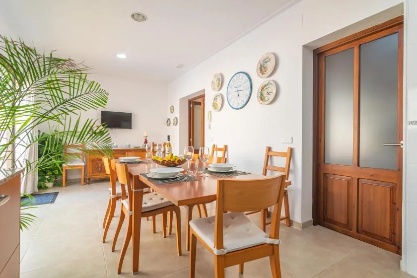 A dining room with a wooden table and chairs beneath decorative wall clocks.