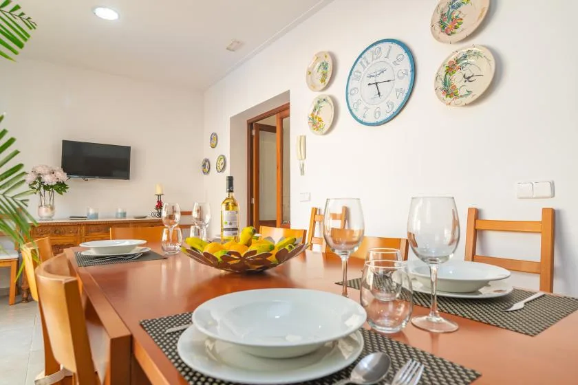 A dining room with a set table and a wall clock.