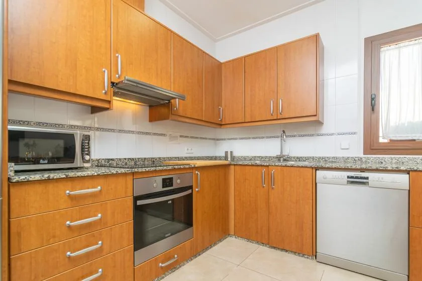 A kitchen with wooden cabinets, a built-in oven, and a dishwasher.