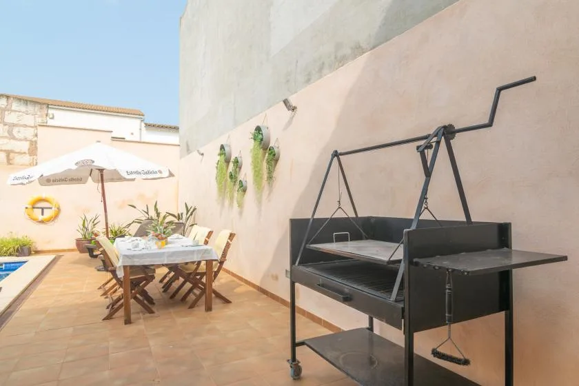 A sunny outdoor patio with a dining table and a metal grill.