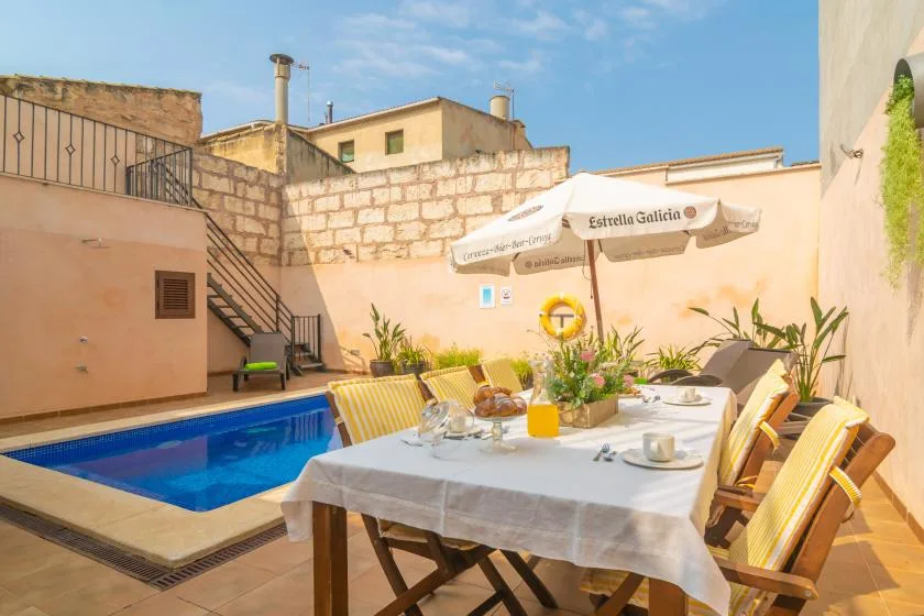 An outdoor dining area beside a small swimming pool, with a table and chairs.