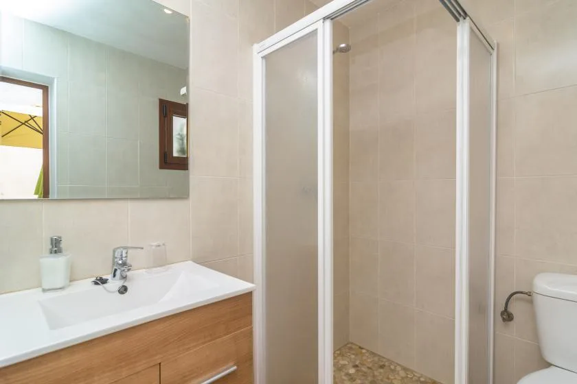 A tiled bathroom with a sink, mirror, and glass shower.