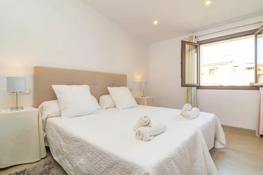 A bright bedroom with a bed and an open window.