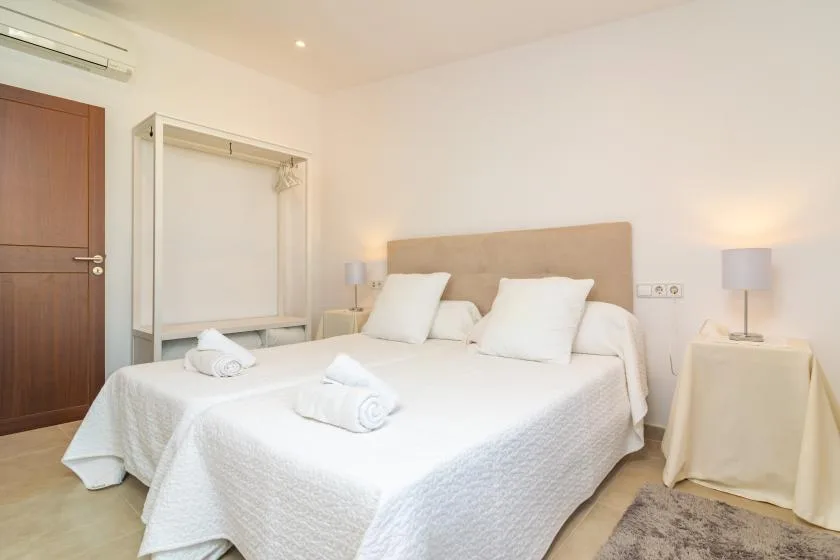A bedroom with a large bed, white bedding, and bedside lamps.