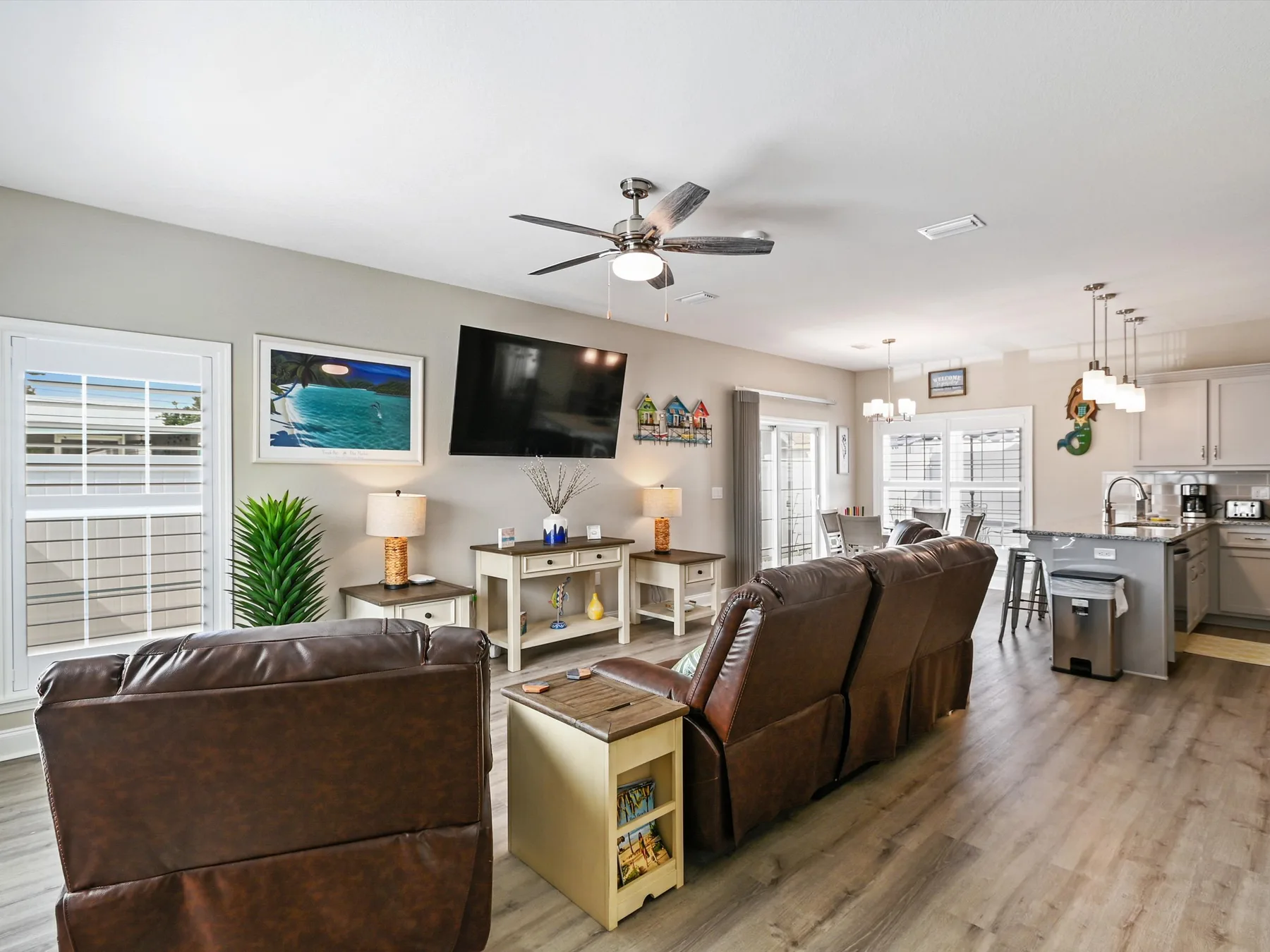 An open-plan living room and kitchen with leather seating and a television.