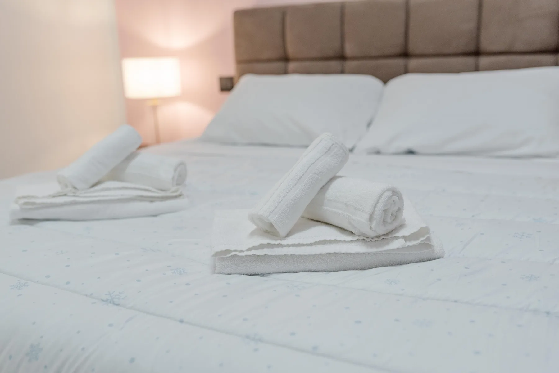 A bedroom with a neatly made bed and folded white towels.