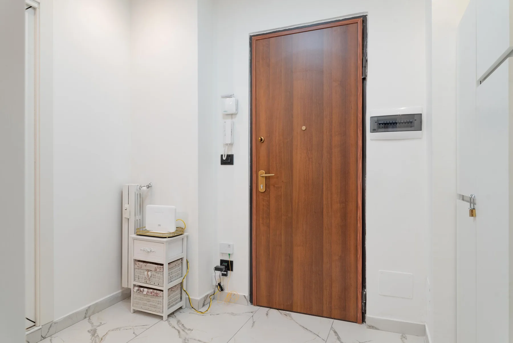 A bright entryway with a wooden door and a small storage shelf.