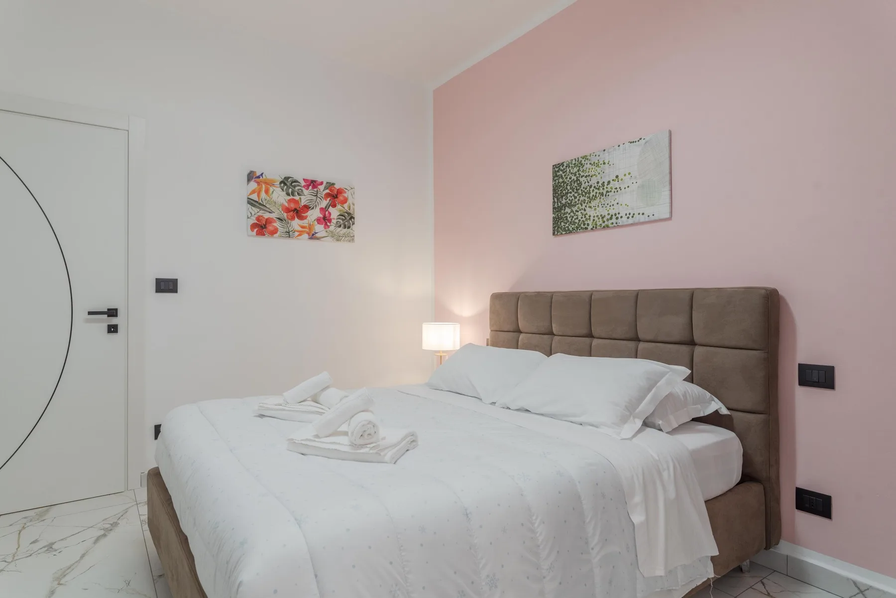 A bedroom with a large bed, white linens, and a padded headboard.