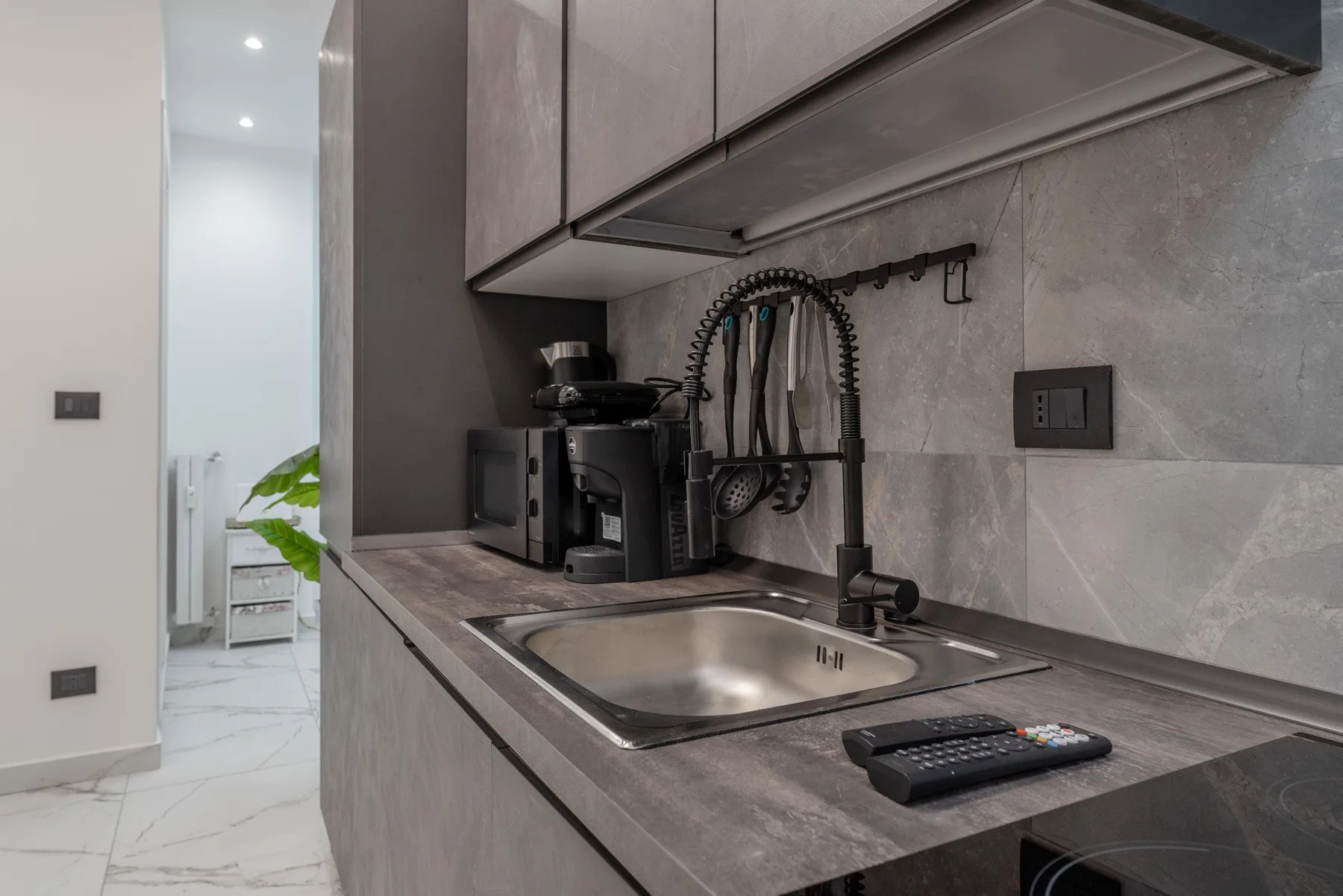 A modern kitchen counter with a stainless-steel sink and coffee maker.
