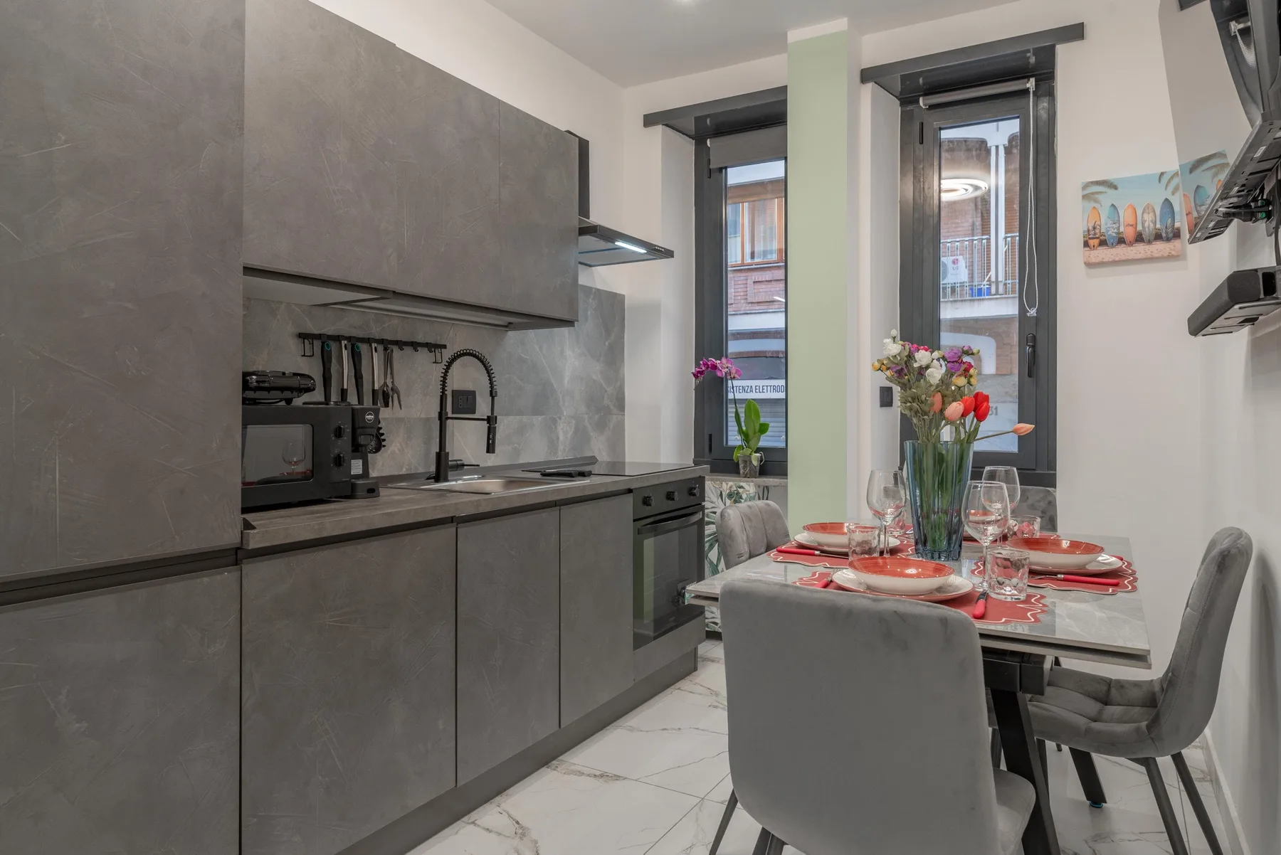 A kitchen and dining area with gray cabinets and a table set near tall windows.