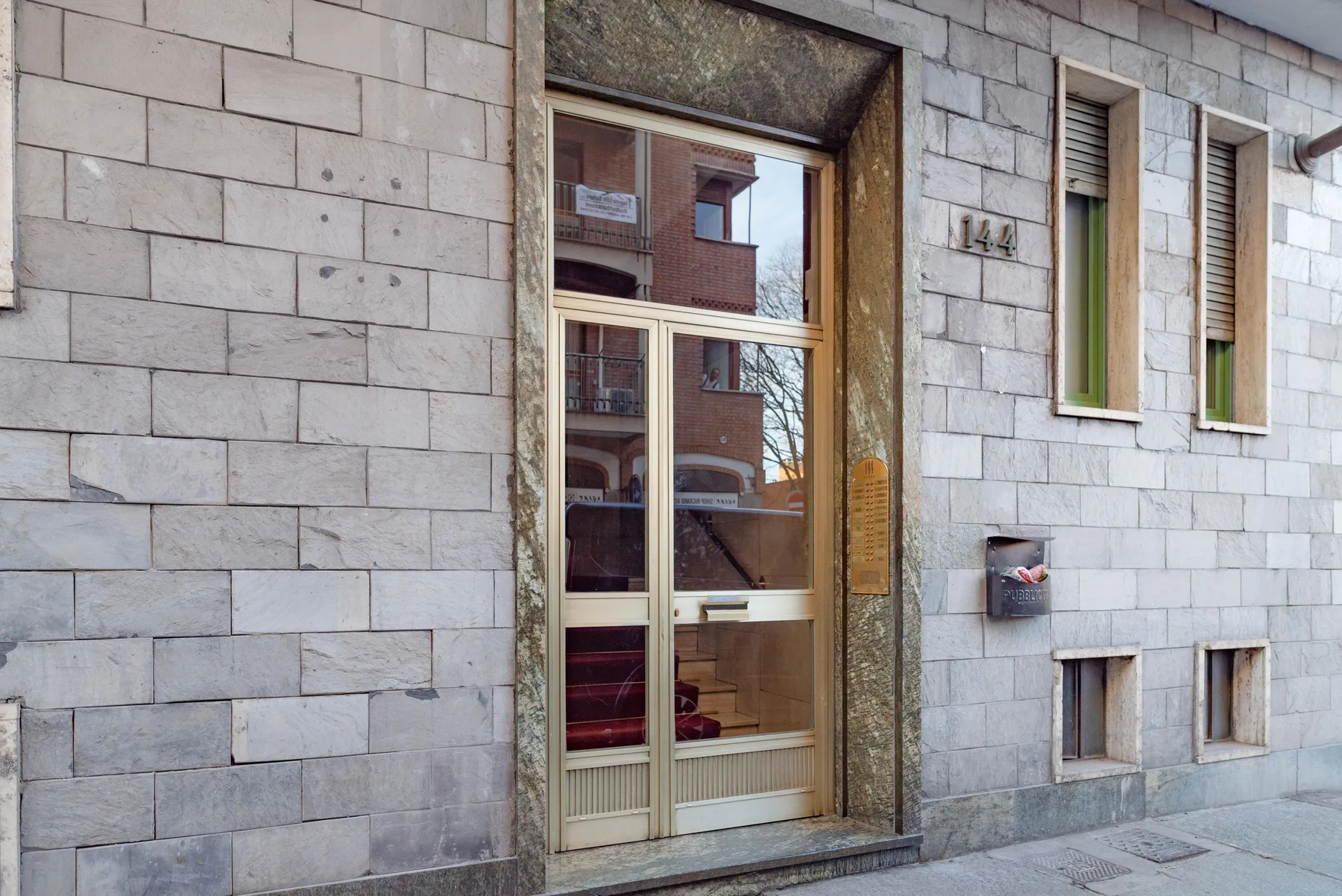 A stone-faced building entrance with a glass door and windows.