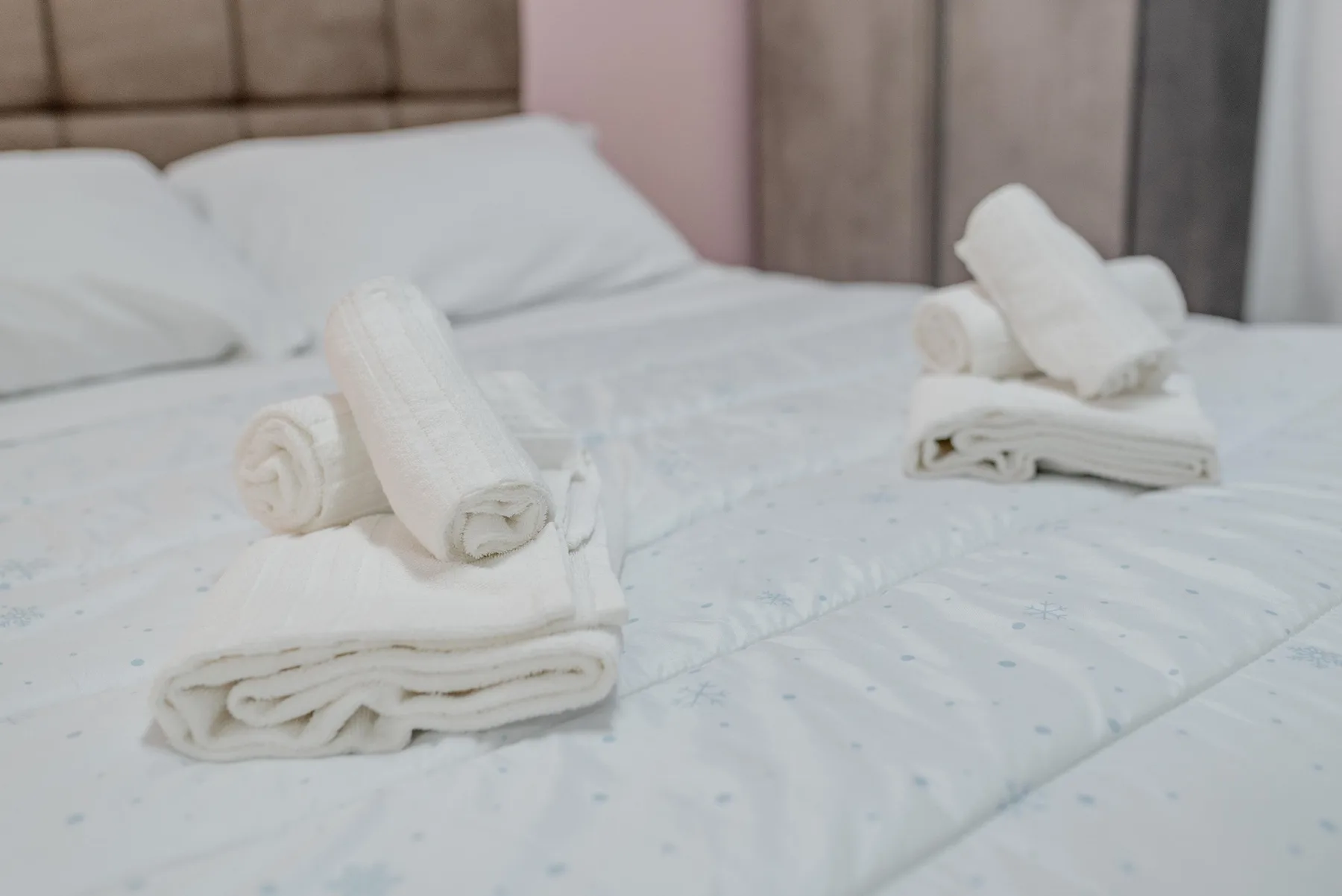 A bedroom with a neatly made bed and folded white towels.