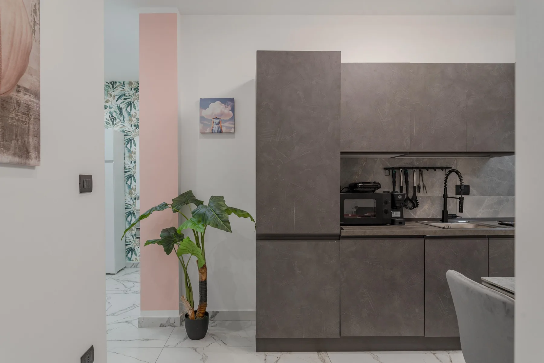 A modern kitchen with dark cabinets, a countertop, and a potted plant.