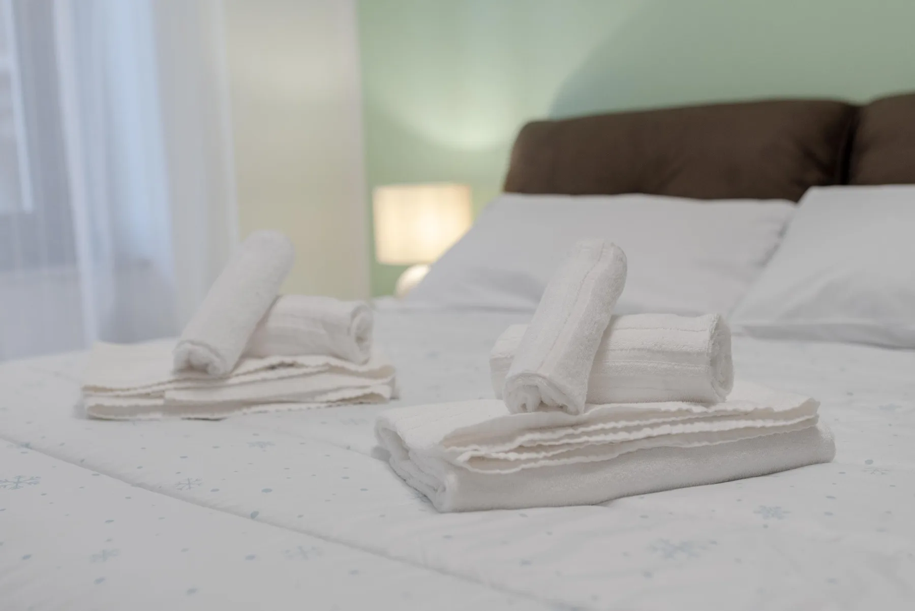 A bedroom with folded white towels arranged on the bed.