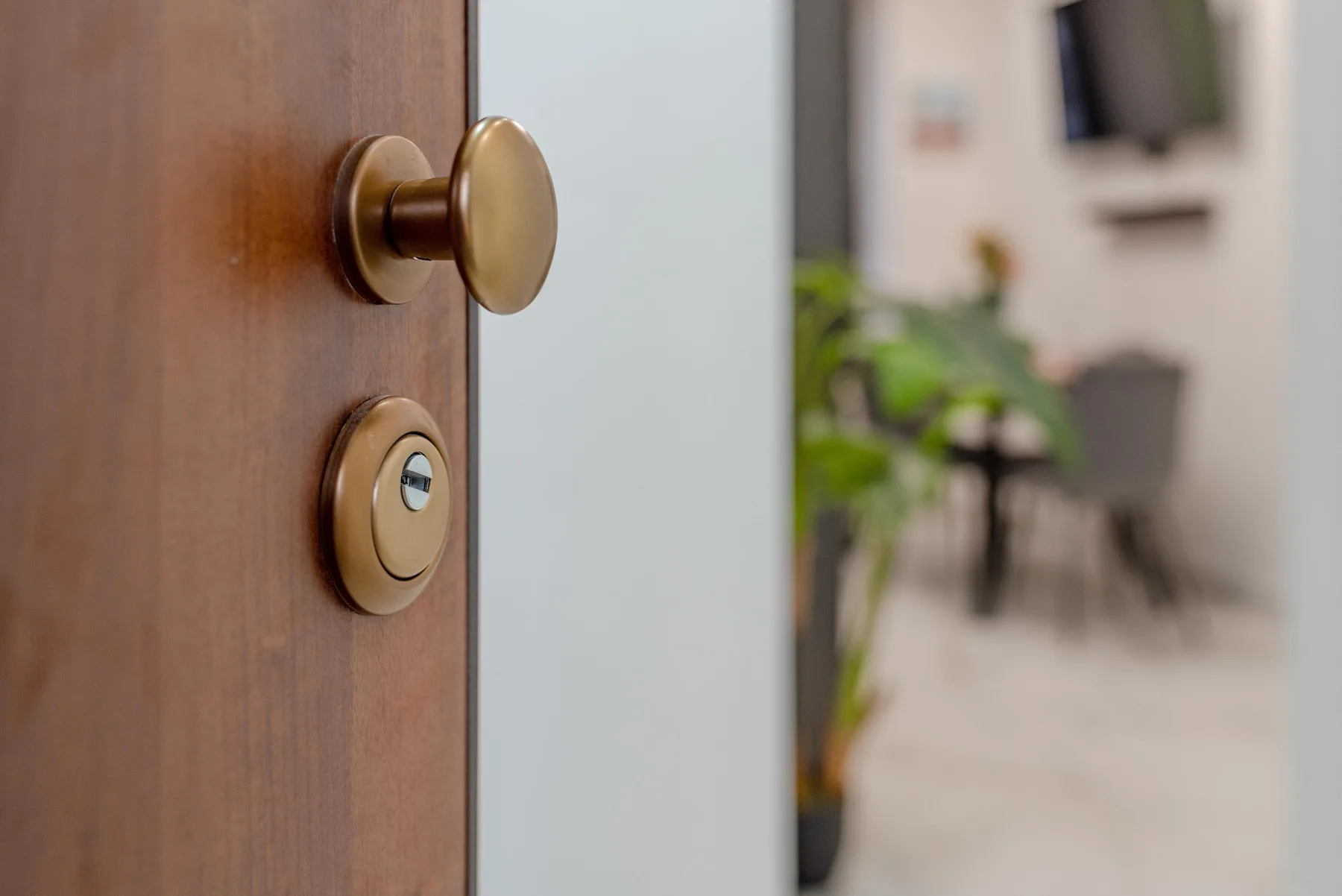 A wooden door with a brass-colored knob opens onto a softly blurred room.