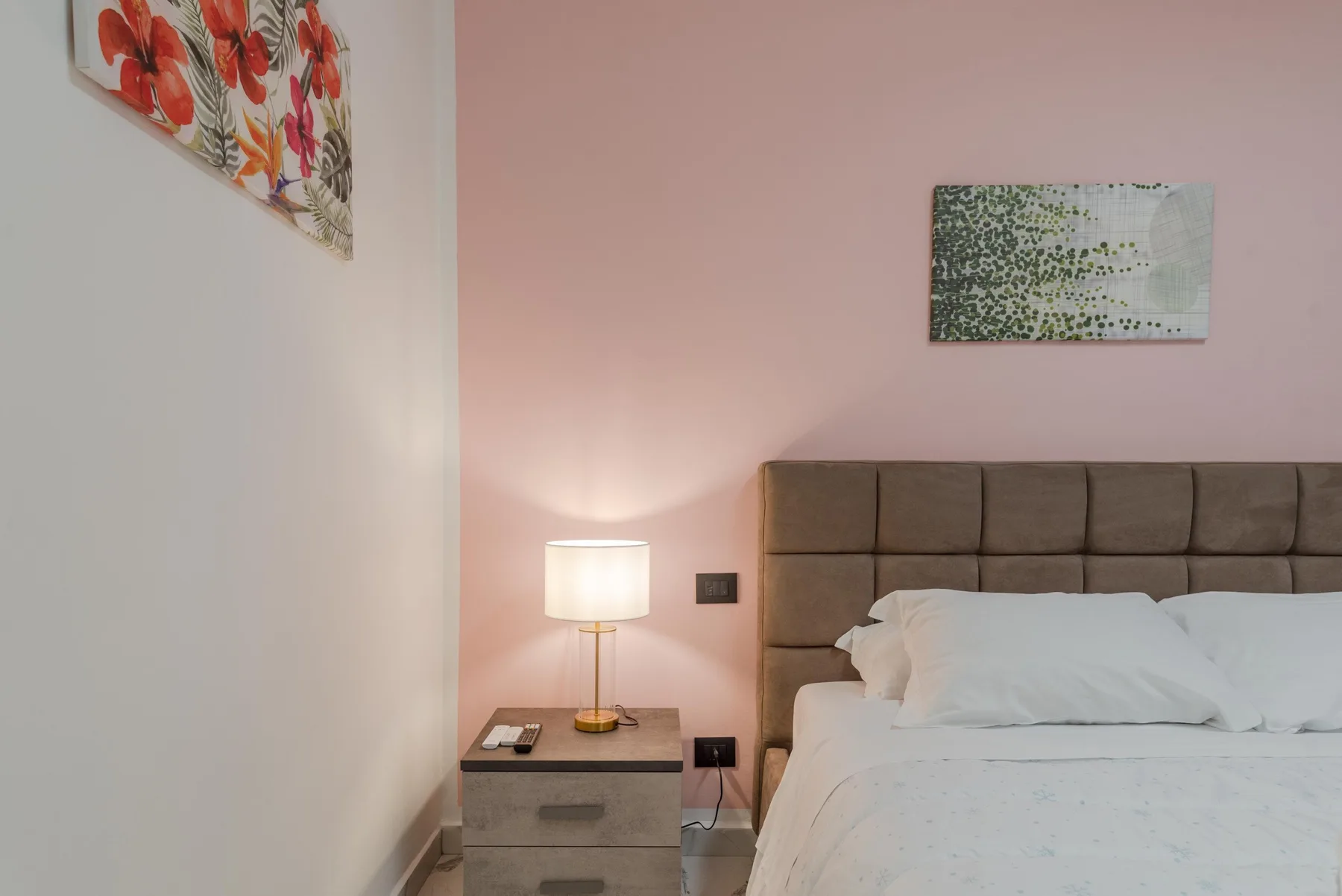 A bedroom with a neatly made bed and a bedside table.