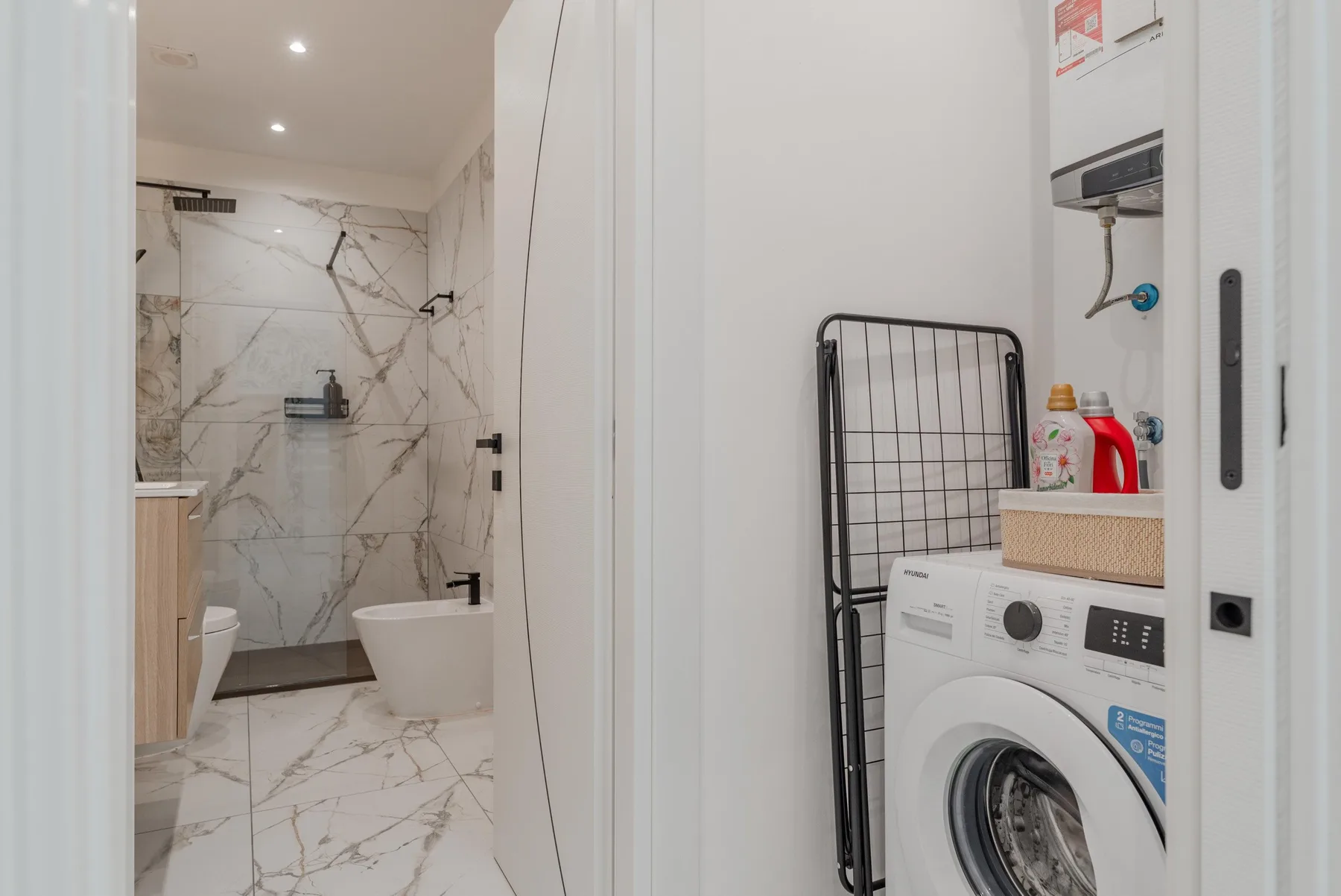 A bathroom with a bathtub and shower beside a laundry area.