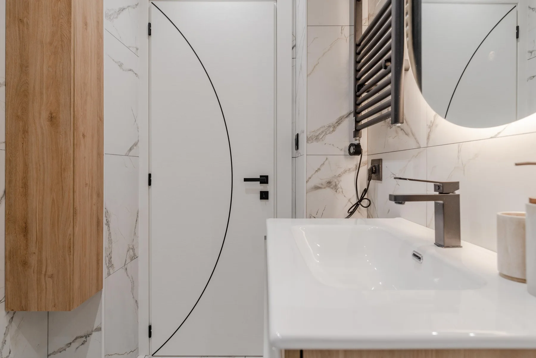A bathroom vanity with a white sink, wall mirror, and wood cabinetry.