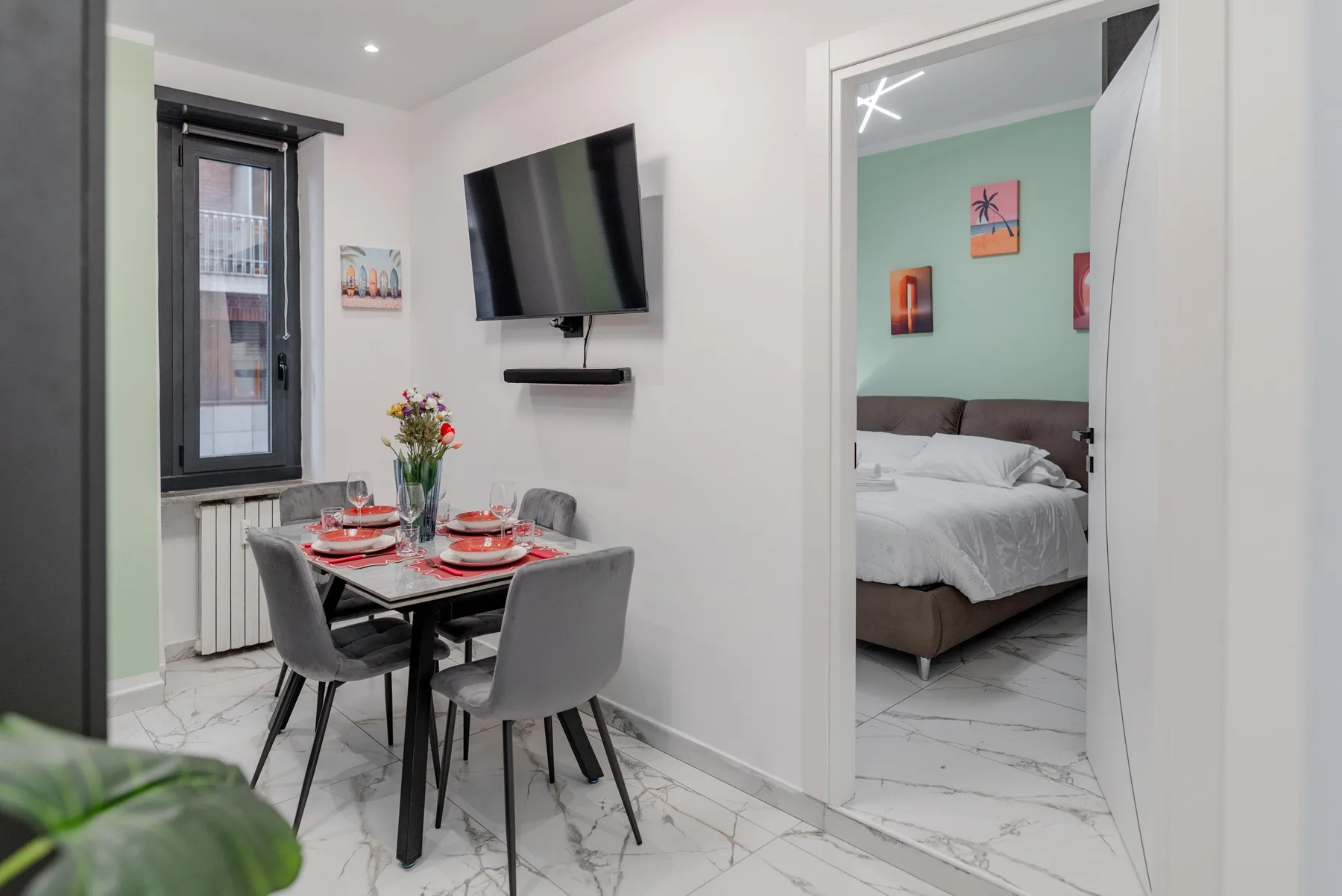 A dining area with a table and chairs beside a doorway to a bedroom.