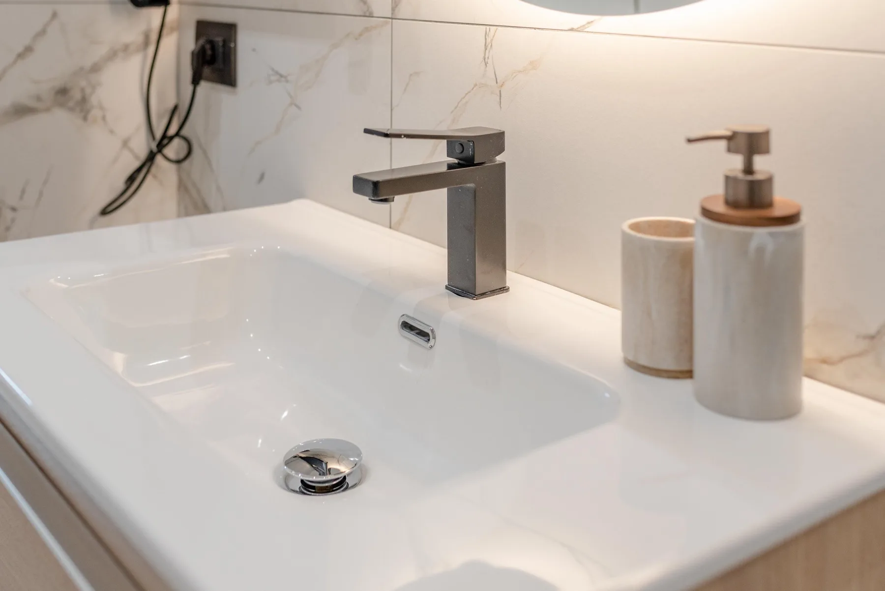 A bathroom sink with a modern faucet and countertop containers.