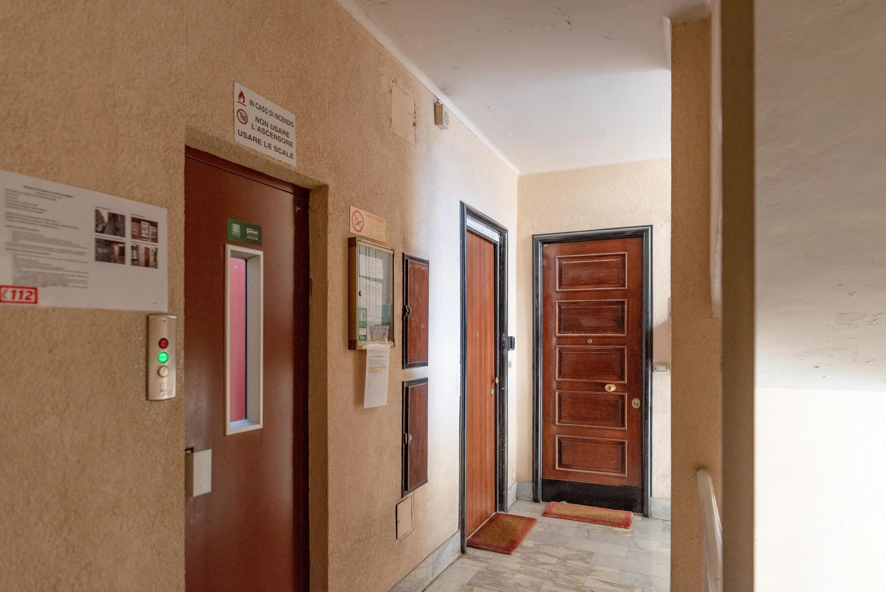 An indoor hallway with several doors and a floor mat.