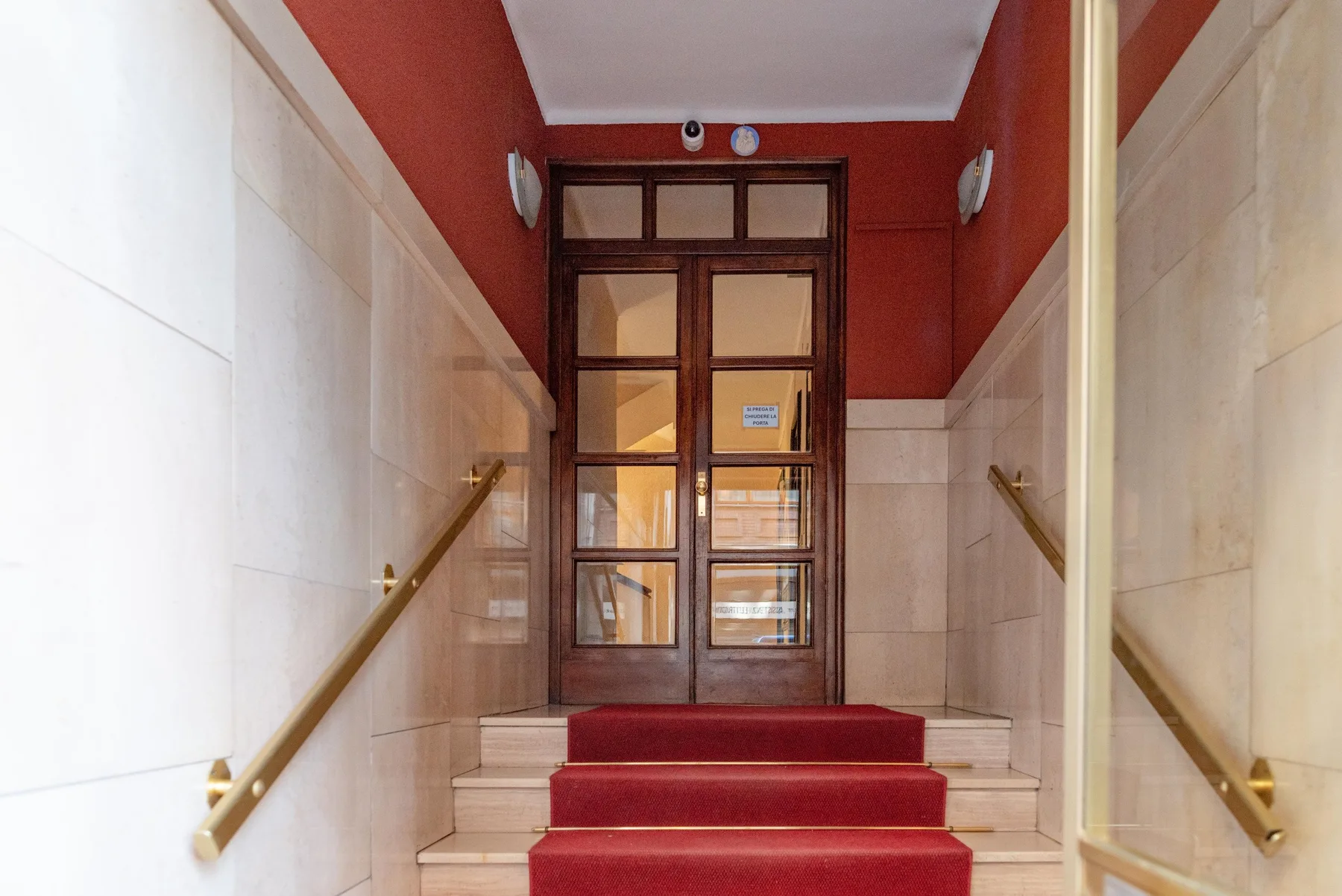 A red-carpeted stairway leads to a dark wooden and glass doorway.