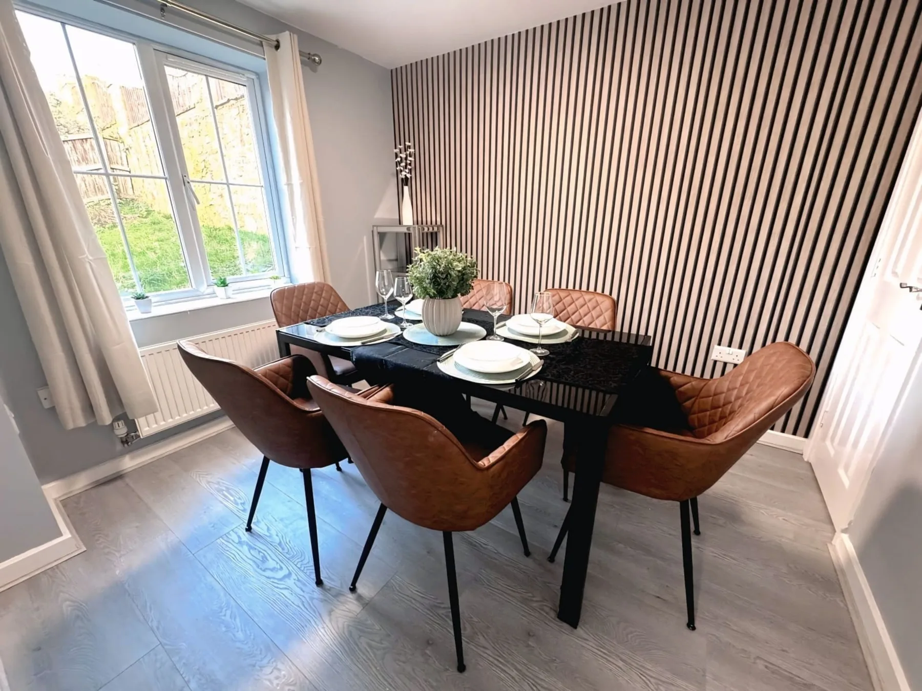 A dining area with a black table set with plates and greenery.