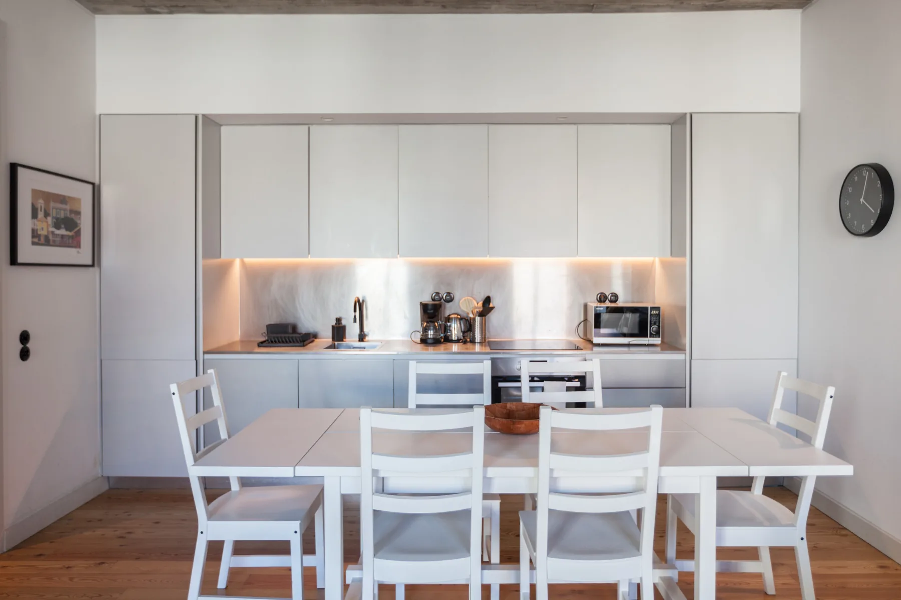 Una cocina luminosa con armarios blancos y una mesa de comedor.