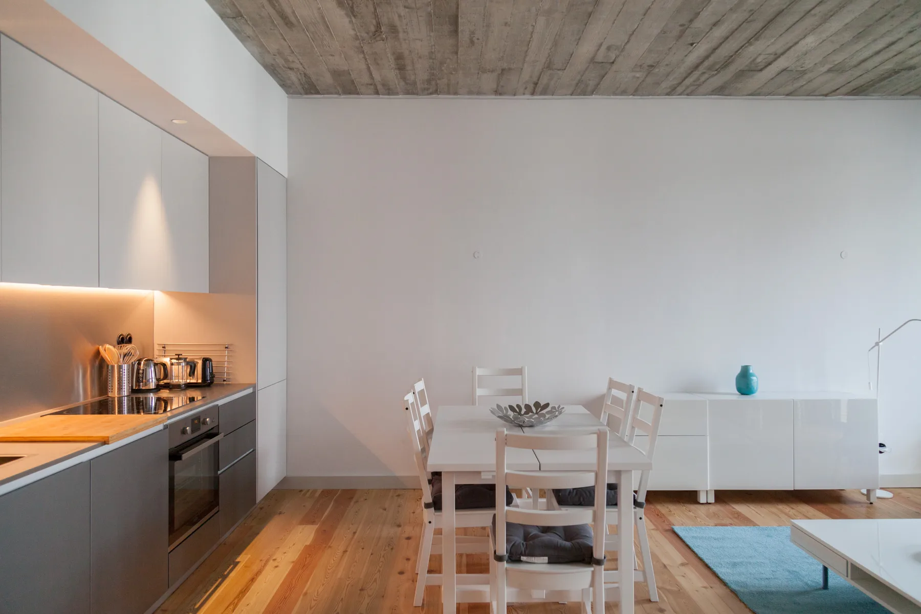 Comedor con mesa y sillas junto a una cocina moderna.