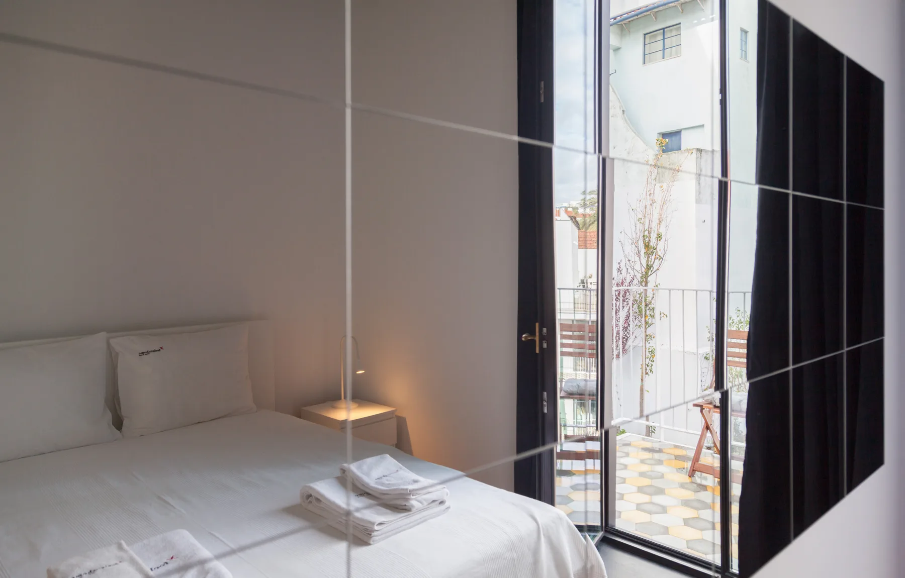 Un dormitorio con una cama junto a una puerta de cristal abierta que da a un balcón.