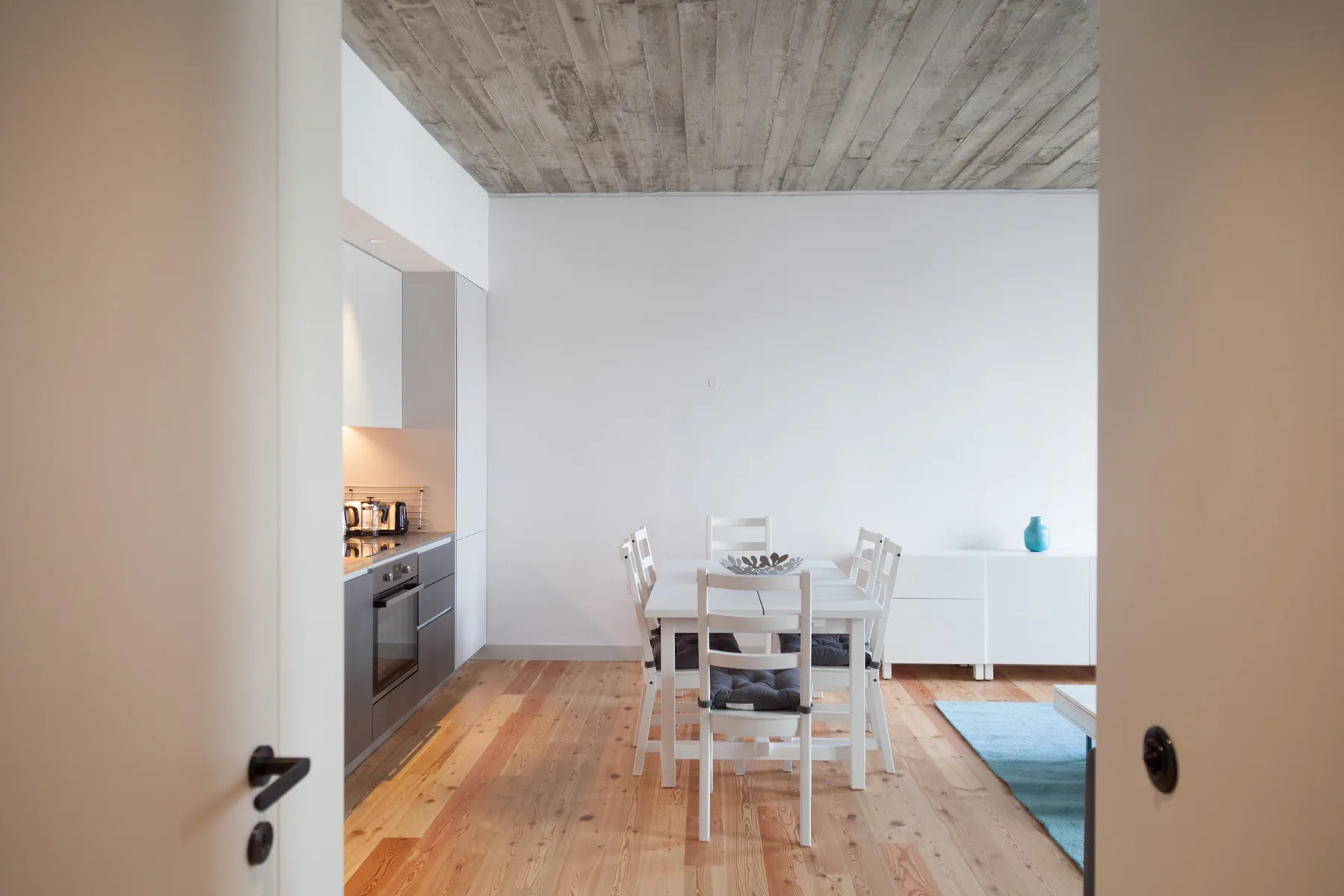 Un comedor con mesa y sillas está junto a una cocina compacta.