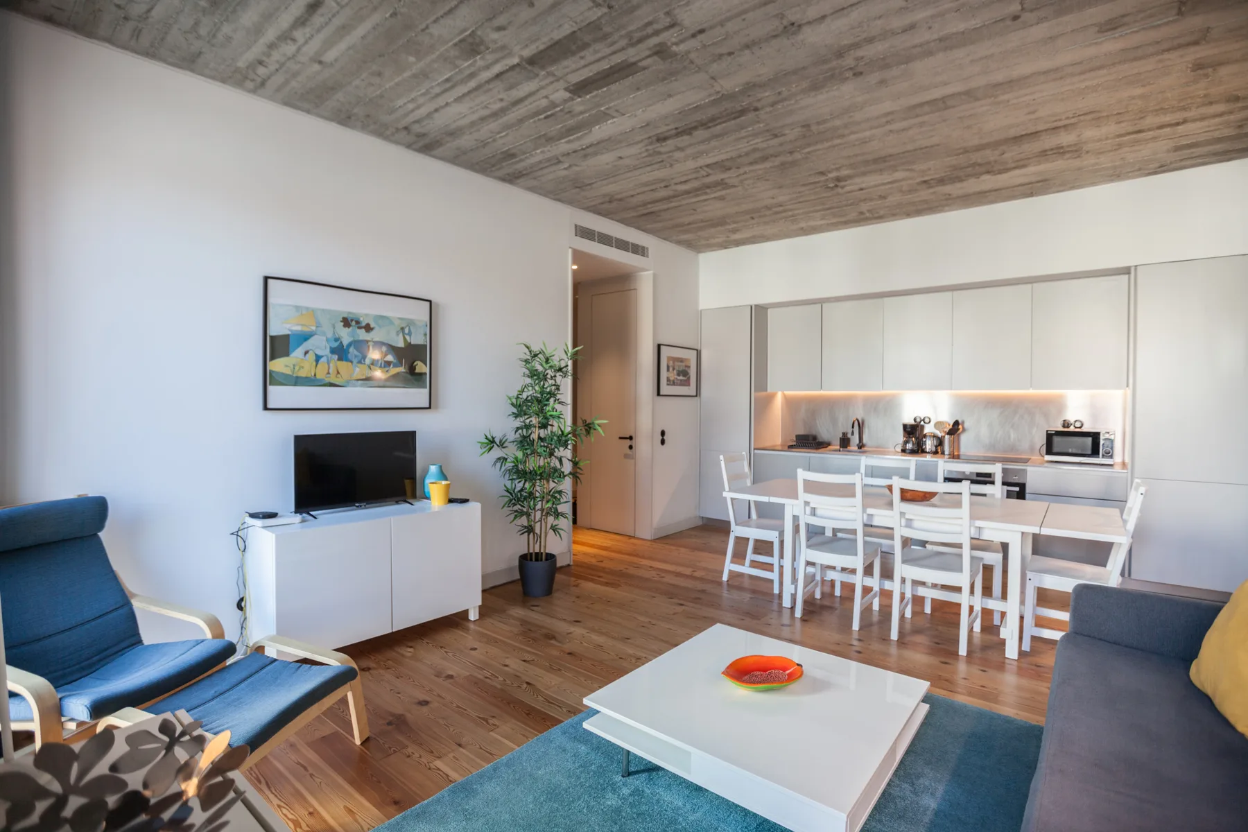 Sala de estar y comedor con cocina y asientos.
