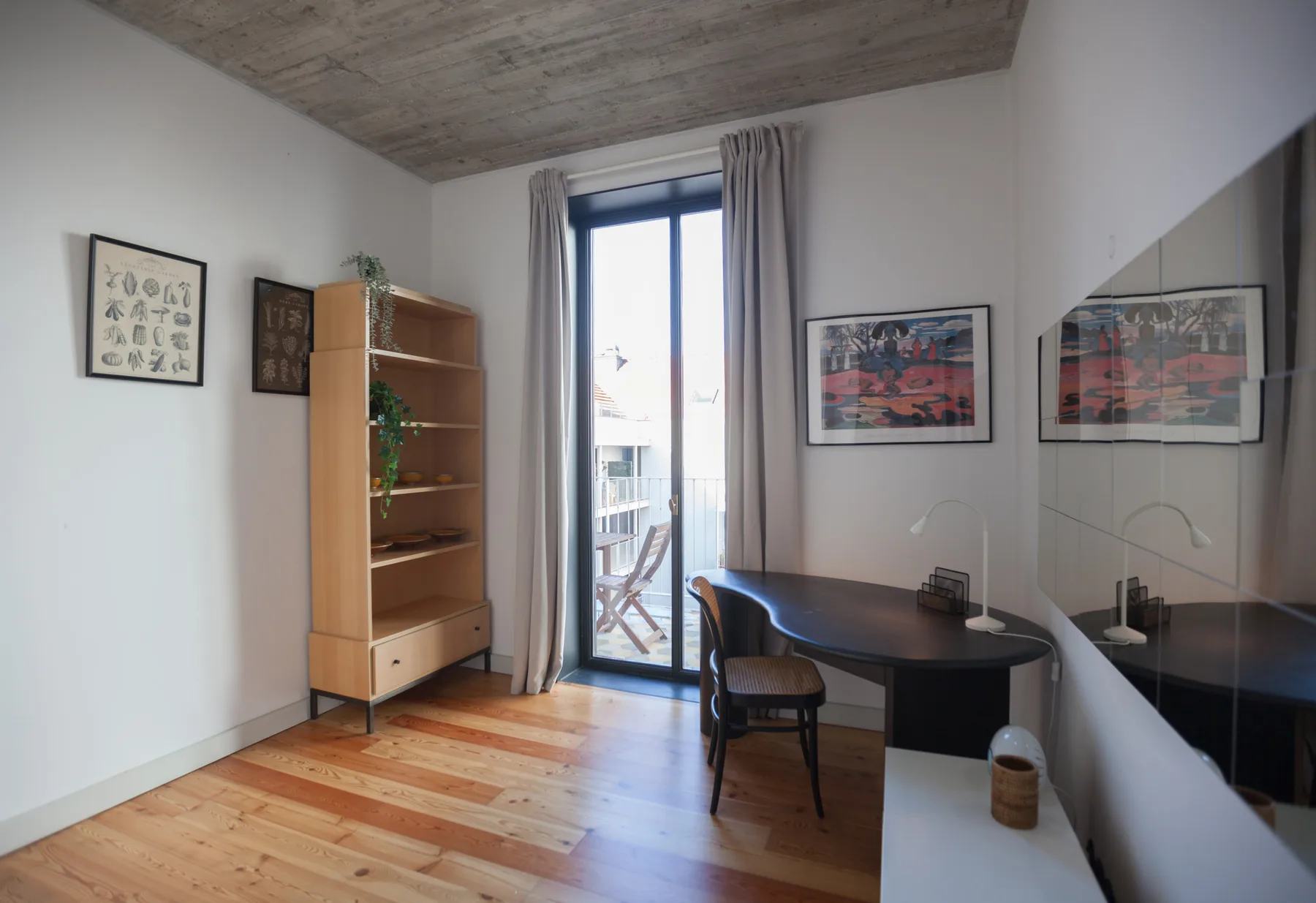 Una pequeña zona de comedor con una mesa redonda está junto a una ventana alta con cortinas.