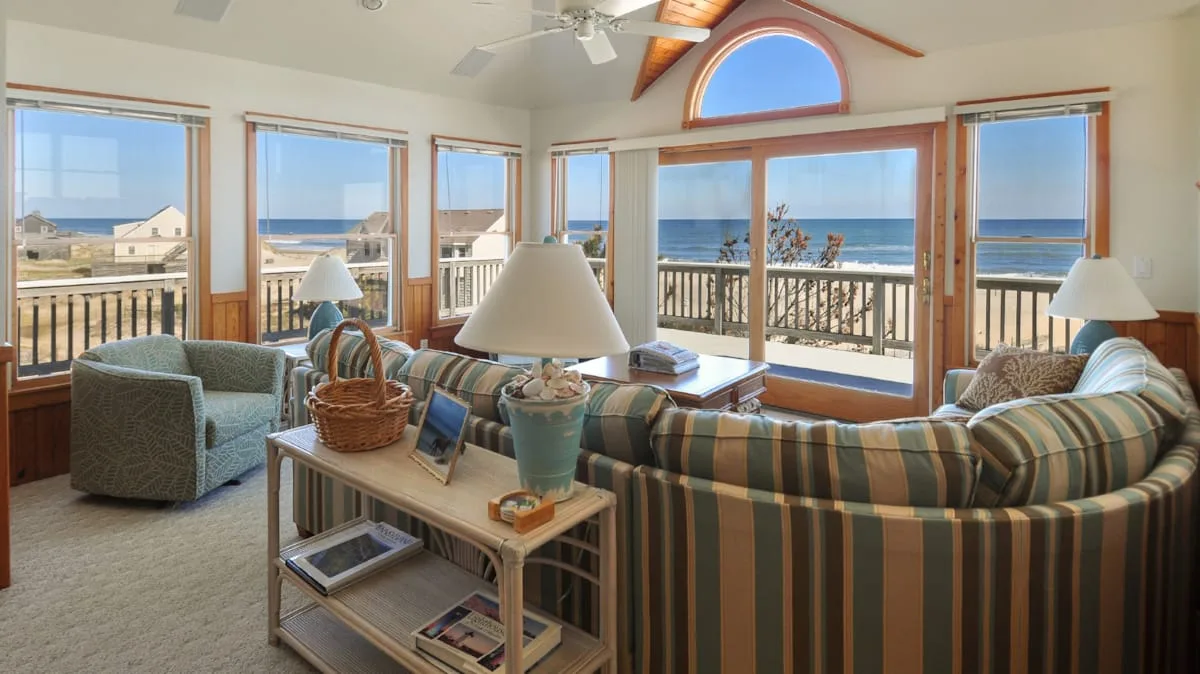 Una luminosa sala de estar con asientos y amplias ventanas con vistas al mar.