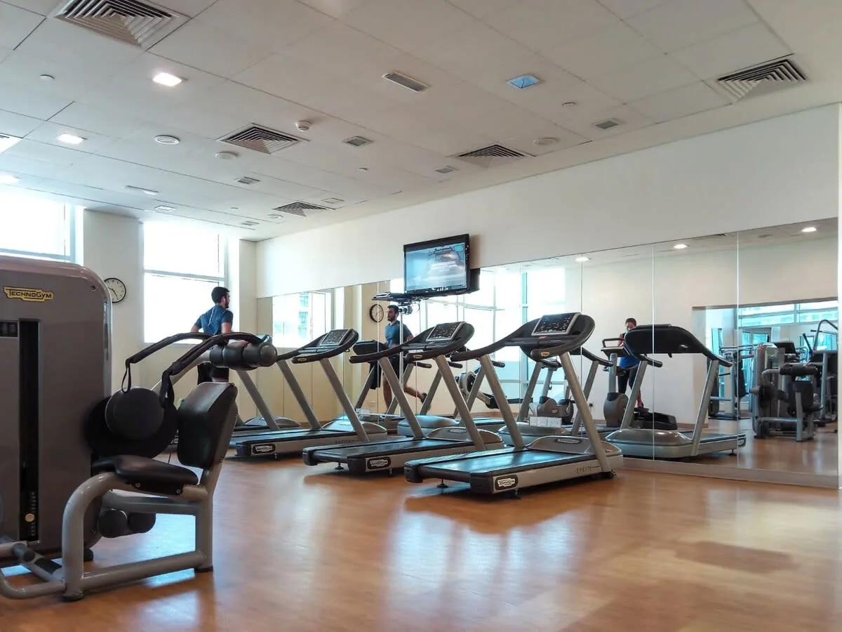 Una sala de ejercicio con cintas de correr y otros equipos.