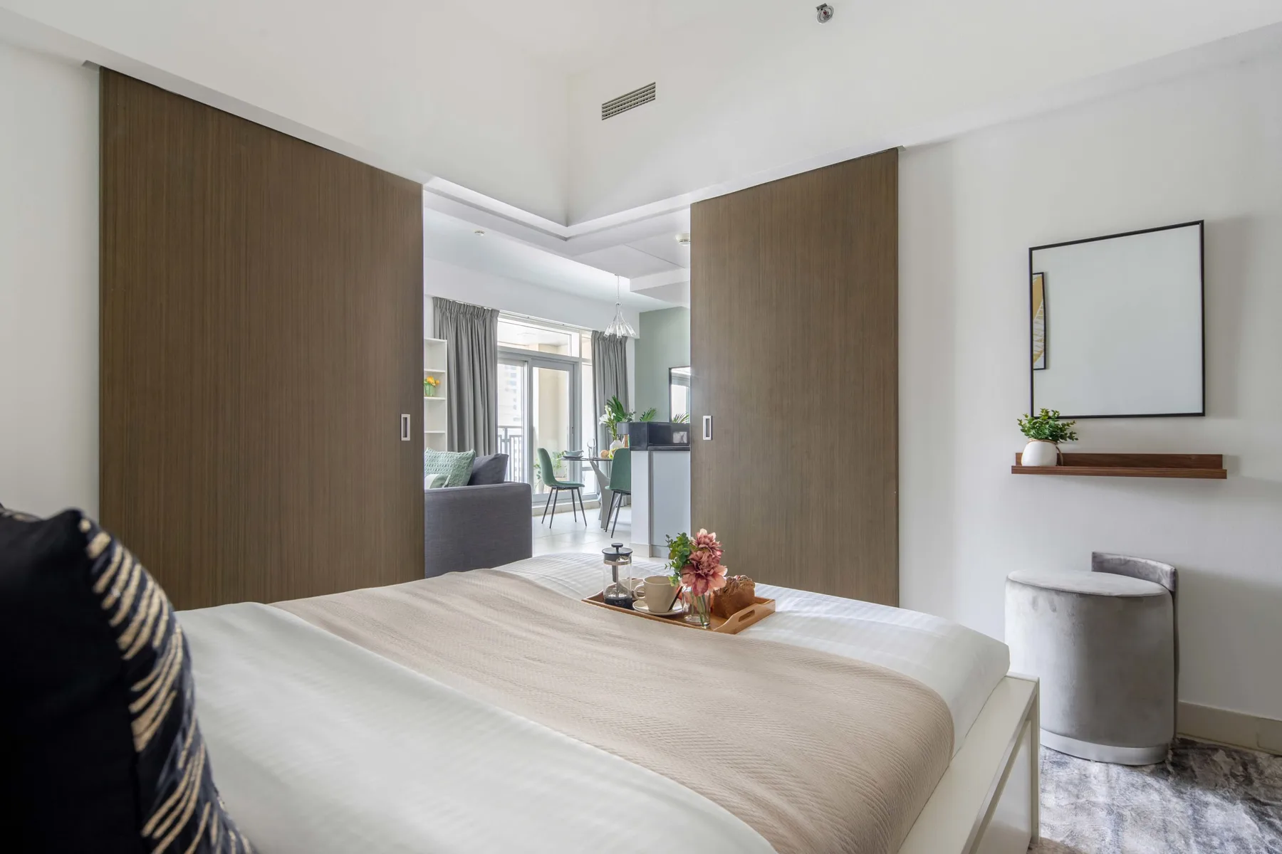 Un dormitorio luminoso con una cama bien tendida y puertas correderas de madera.