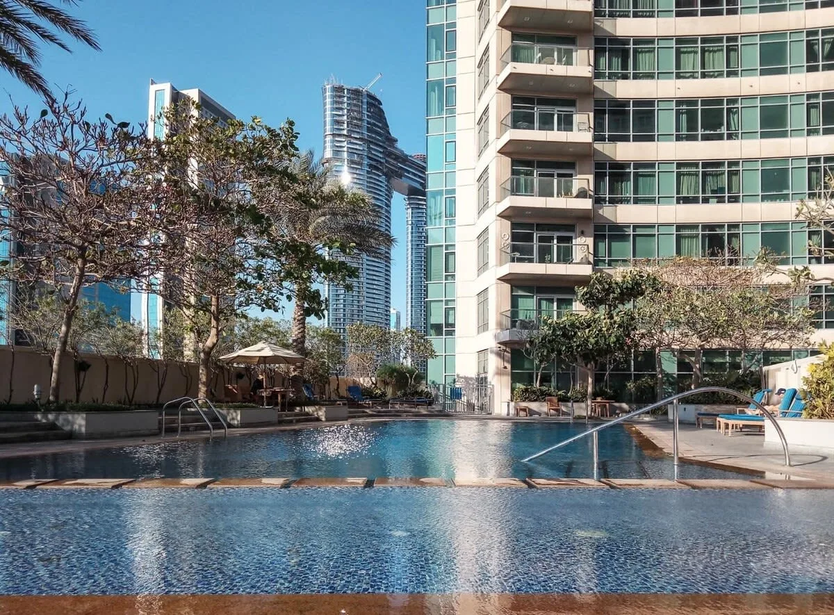 Una piscina al aire libre está junto a un edificio moderno de gran altura.