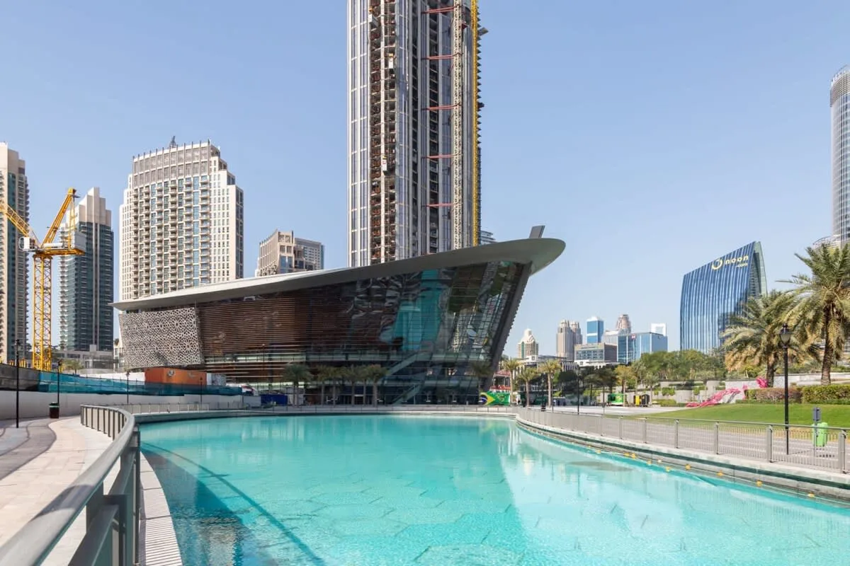 Una piscina al aire libre junto a un edificio moderno y torres de la ciudad.