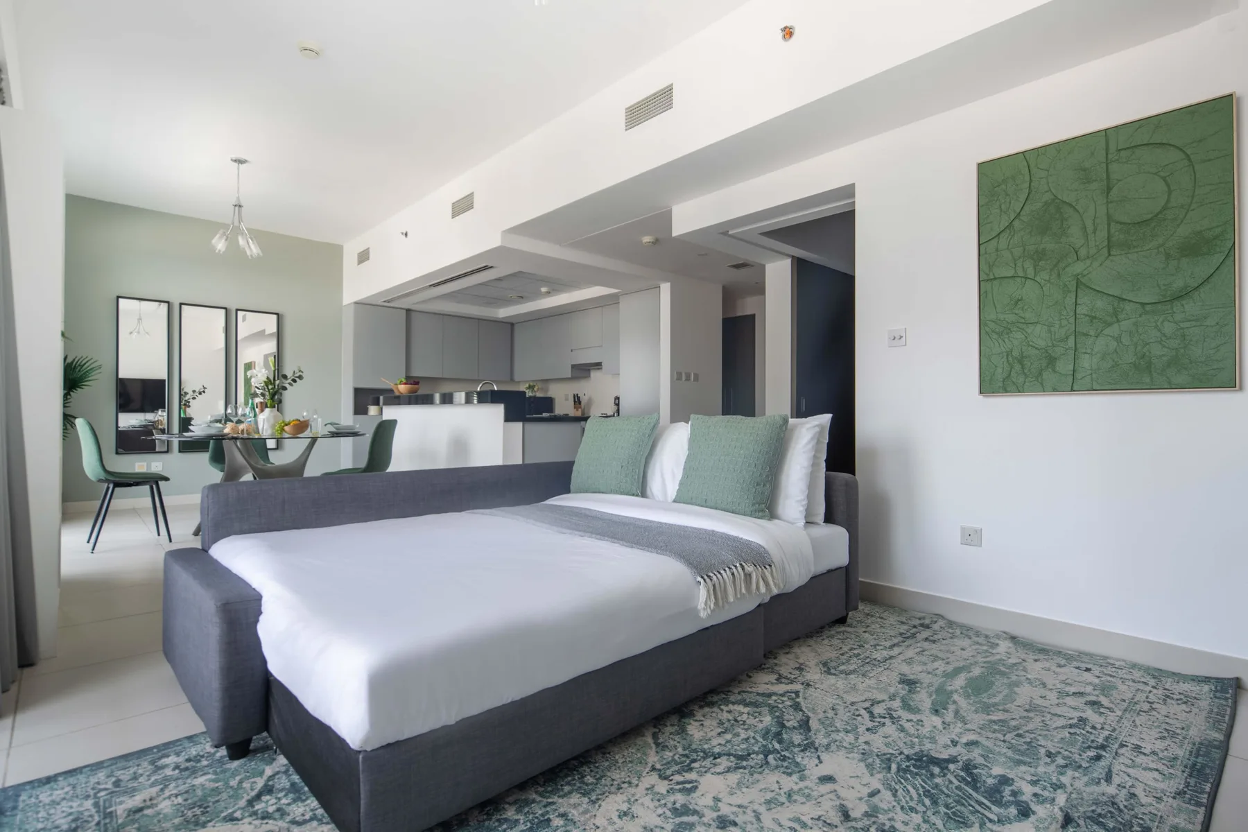 Un dormitorio con una cama grande, una mesa de comedor y una cocina abierta.