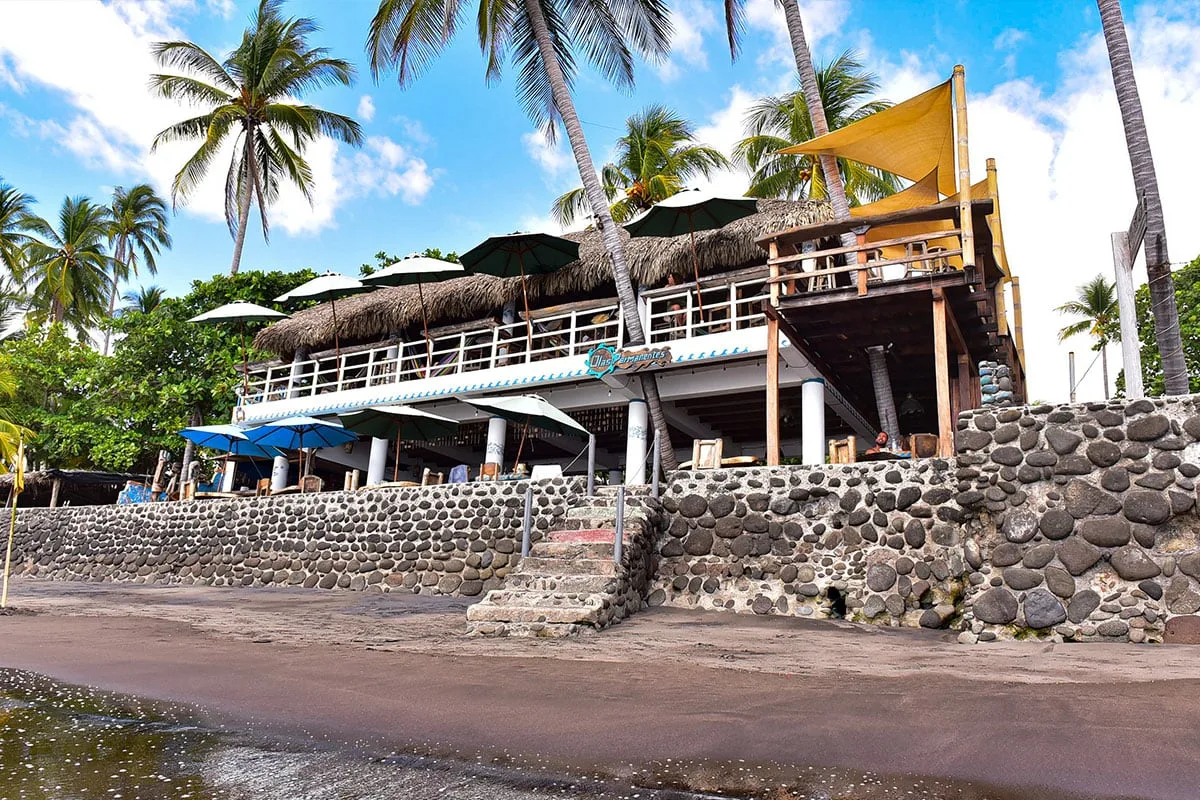 Terraza del restaurante bajo una palapa junto al mar.