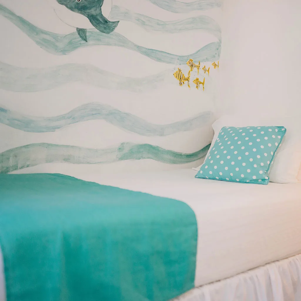 Dormitorio con decoración marítima y una colcha turquesa.