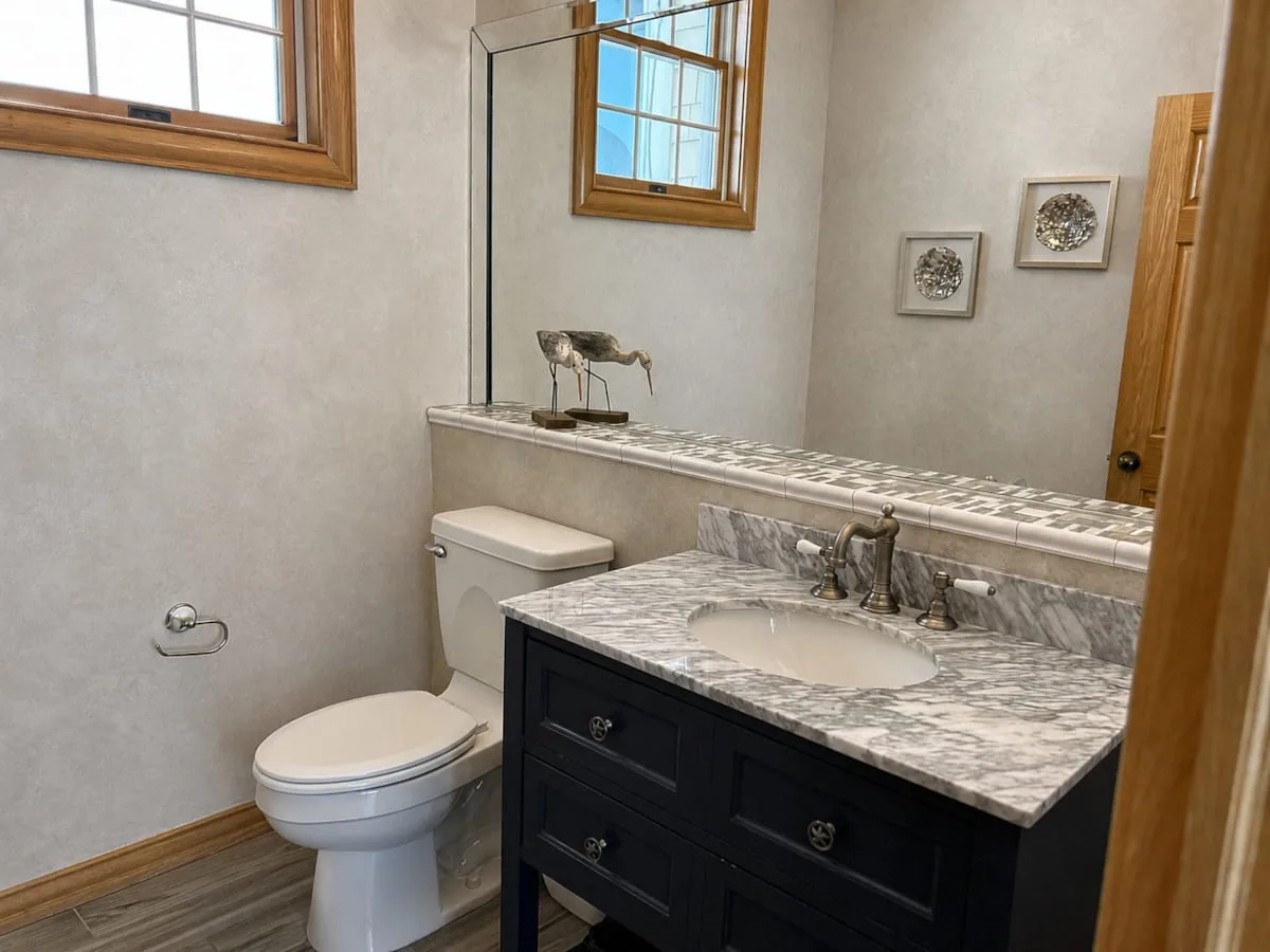 Un baño con lavabo, inodoro y un espejo grande en la pared.