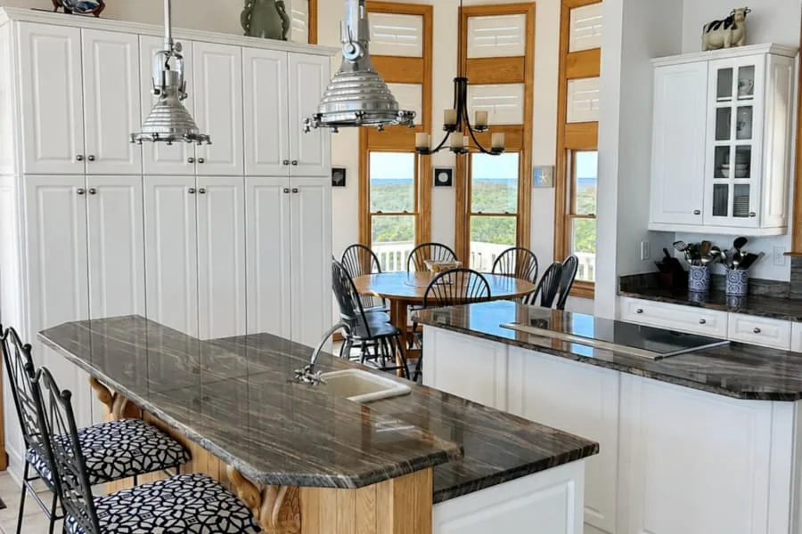 Una cocina luminosa con una isla grande y una mesa de comedor junto a ventanas altas.