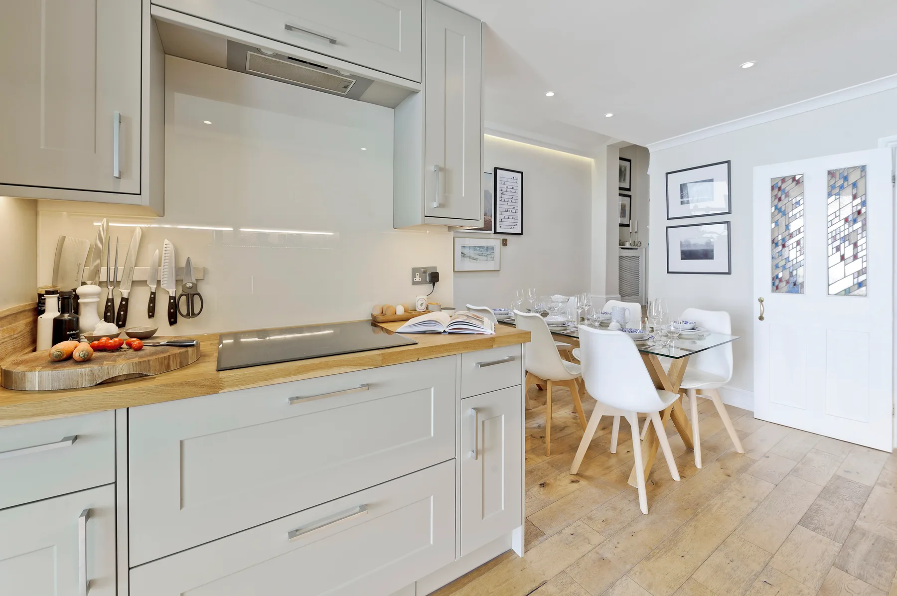 A bright kitchen opens into a dining area with a table and seating.