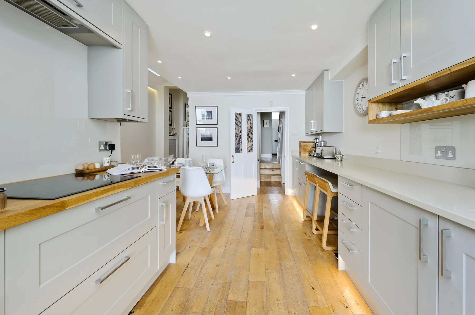 Una cocina luminosa con armarios blancos, encimeras de madera y una mesa de comedor.